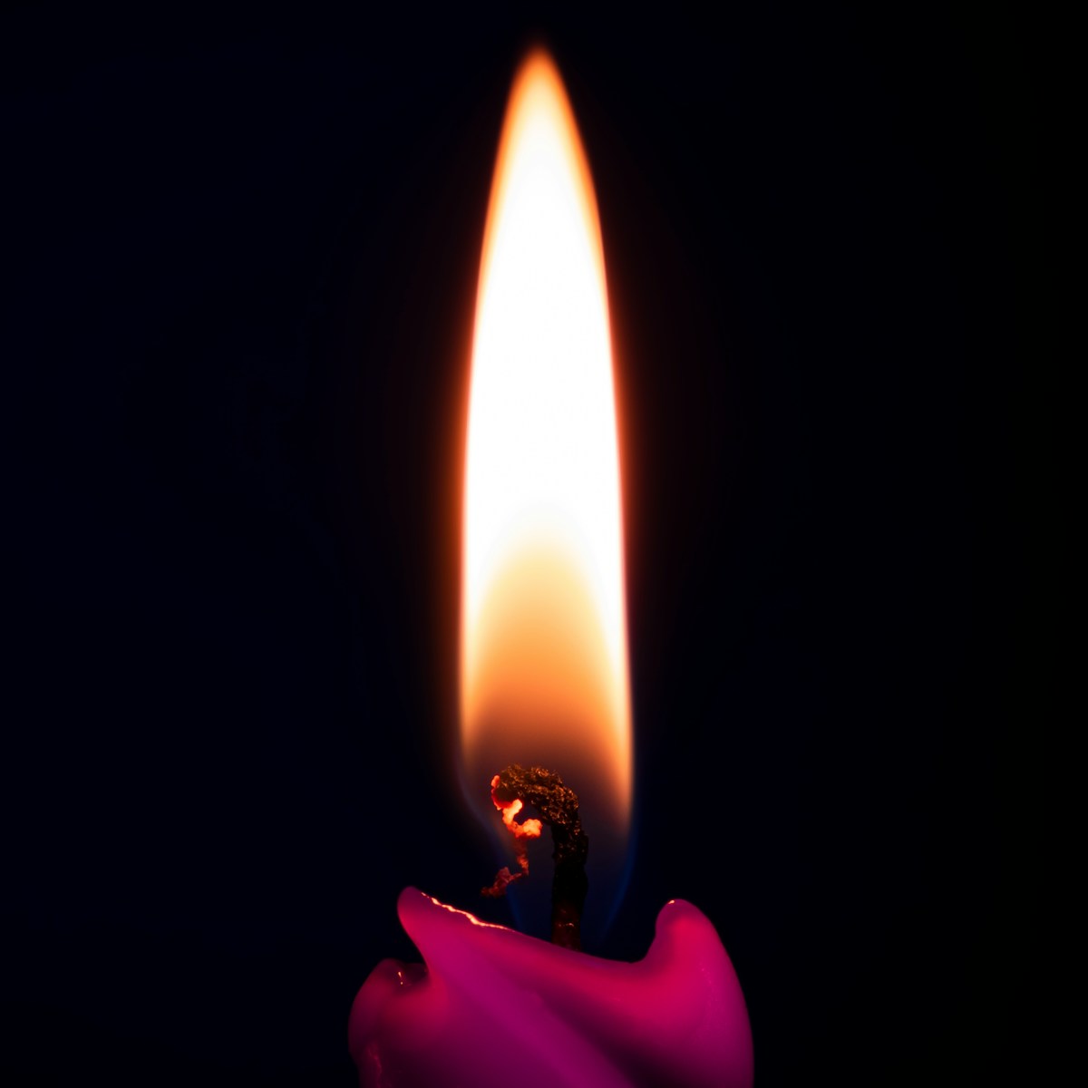 a lit candle in the dark with a dark background